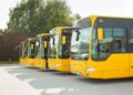 Vários ônibus amarelos estão parados lado a lado