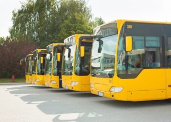 Vários ônibus amarelos estão parados lado a lado